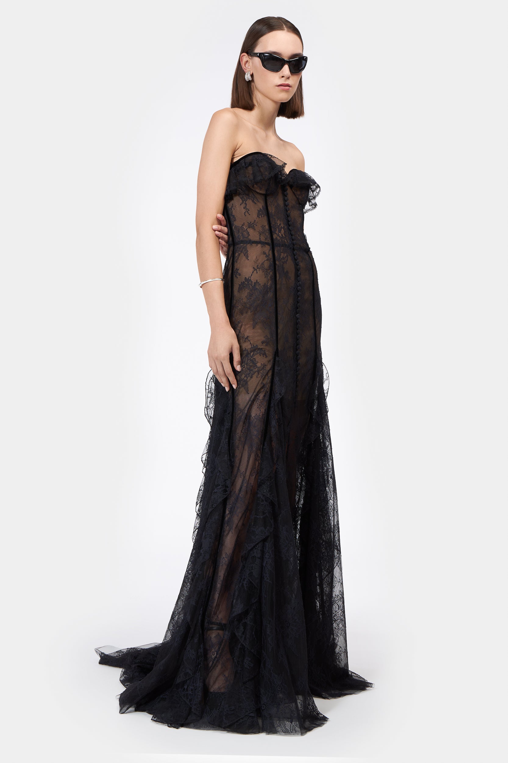 Rosaline Bustier Lace Gown in black with sheer lace detailing, strapless design, and floor-length silhouette. Elegant evening dress with a fitted bodice.