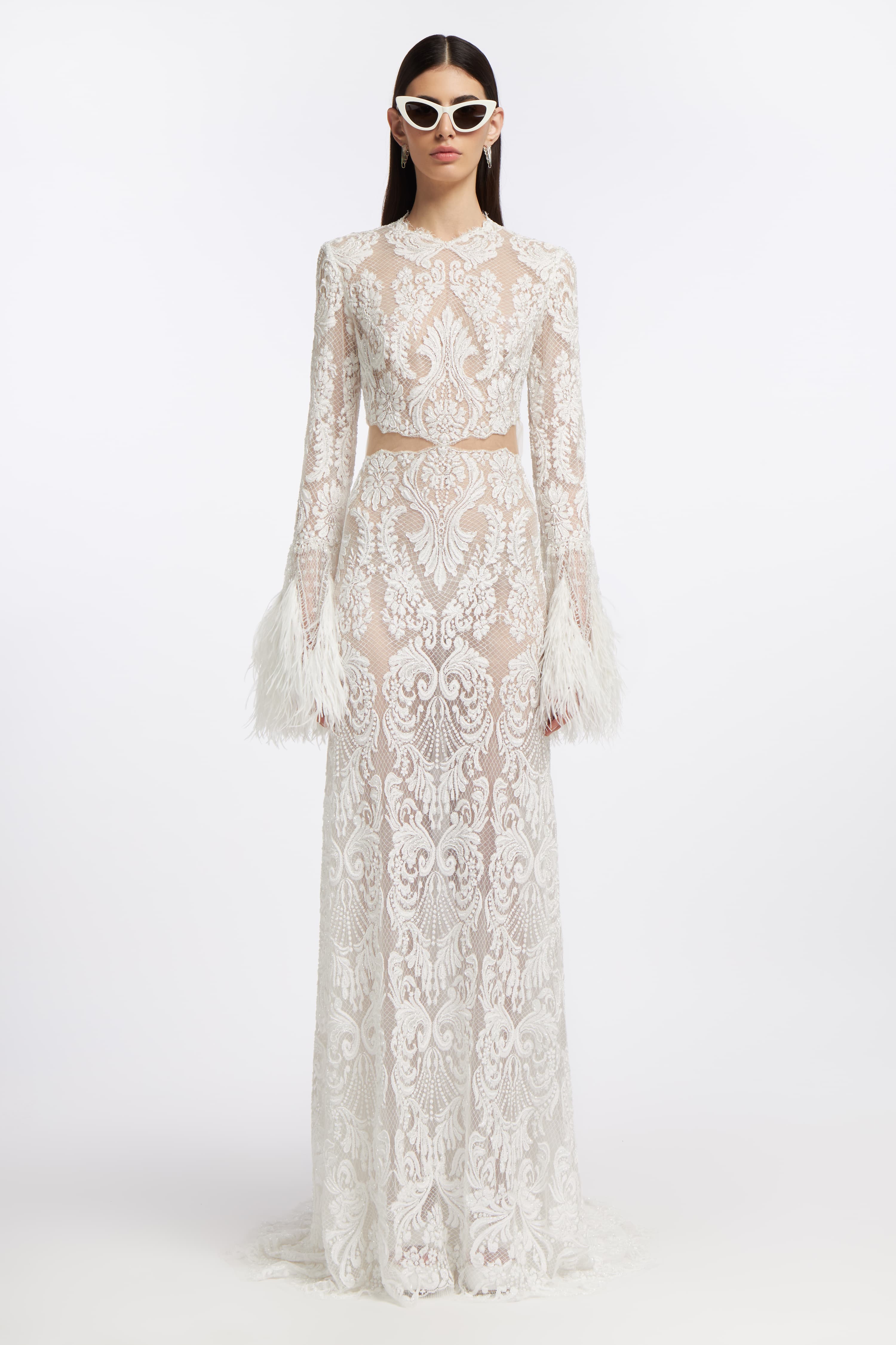 Panorea Beaded Lace Gown featuring intricate lace detailing, long sleeves with feathered cuffs, and a floor-length silhouette for a bridal look.
