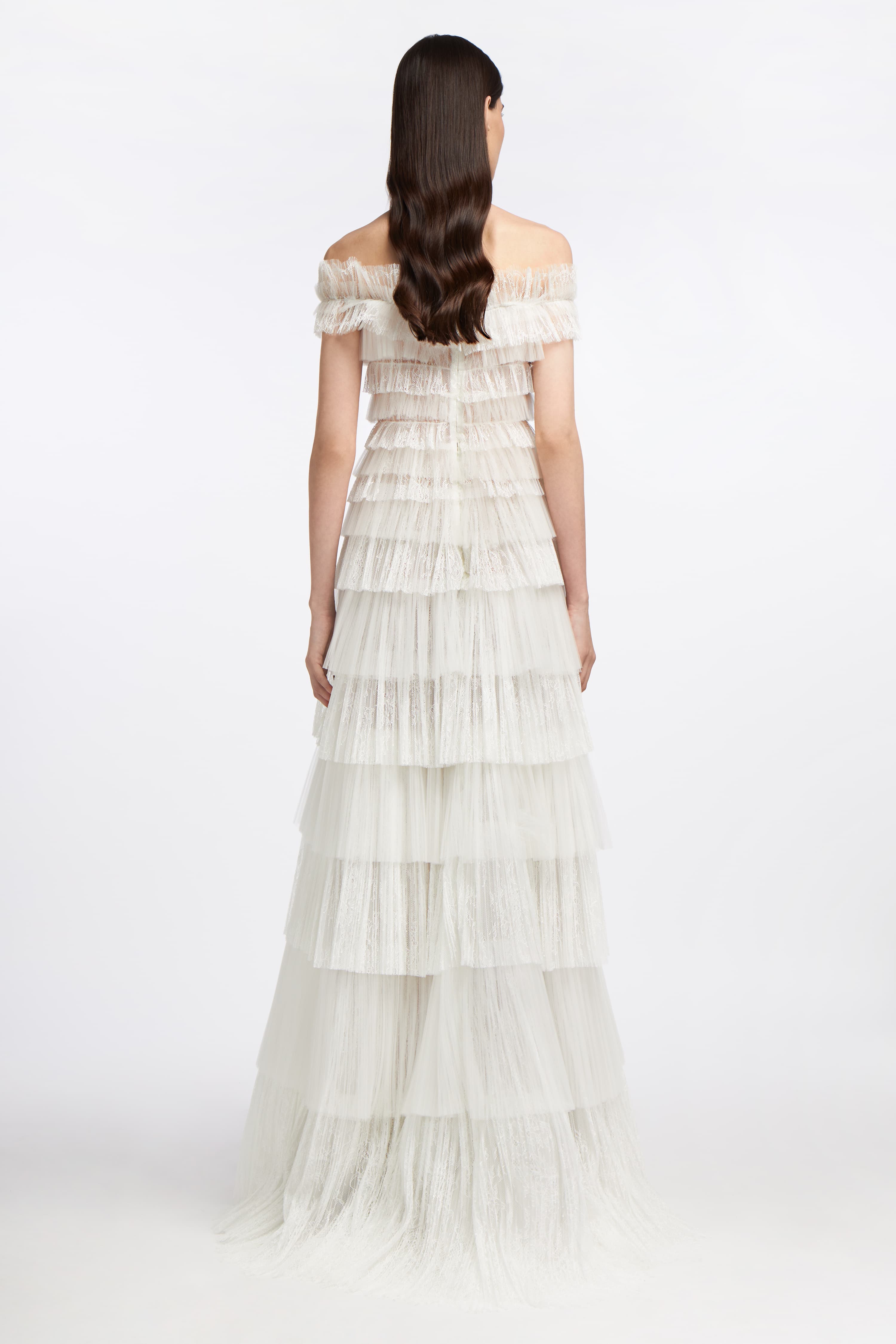 Back view of the Amalthia Plissé Lace Gown with cascading lace tiers and an off-the-shoulder neckline, designed for a romantic bridal appearance.