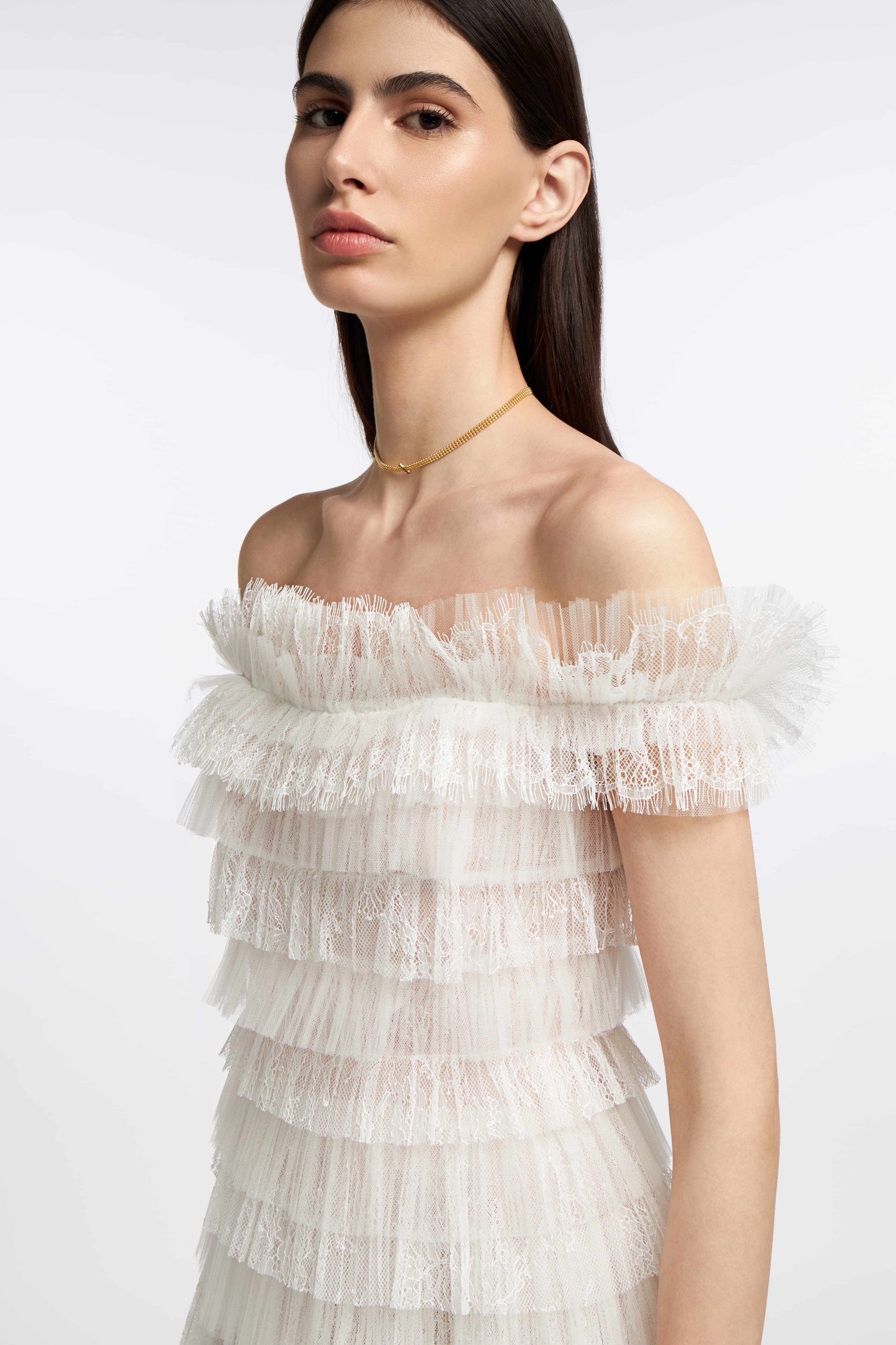 Close-up of the Amalthia Plissé Lace Gown showcasing delicate lace ruffles and an off-the-shoulder design, ideal for an elegant bridal ensemble.