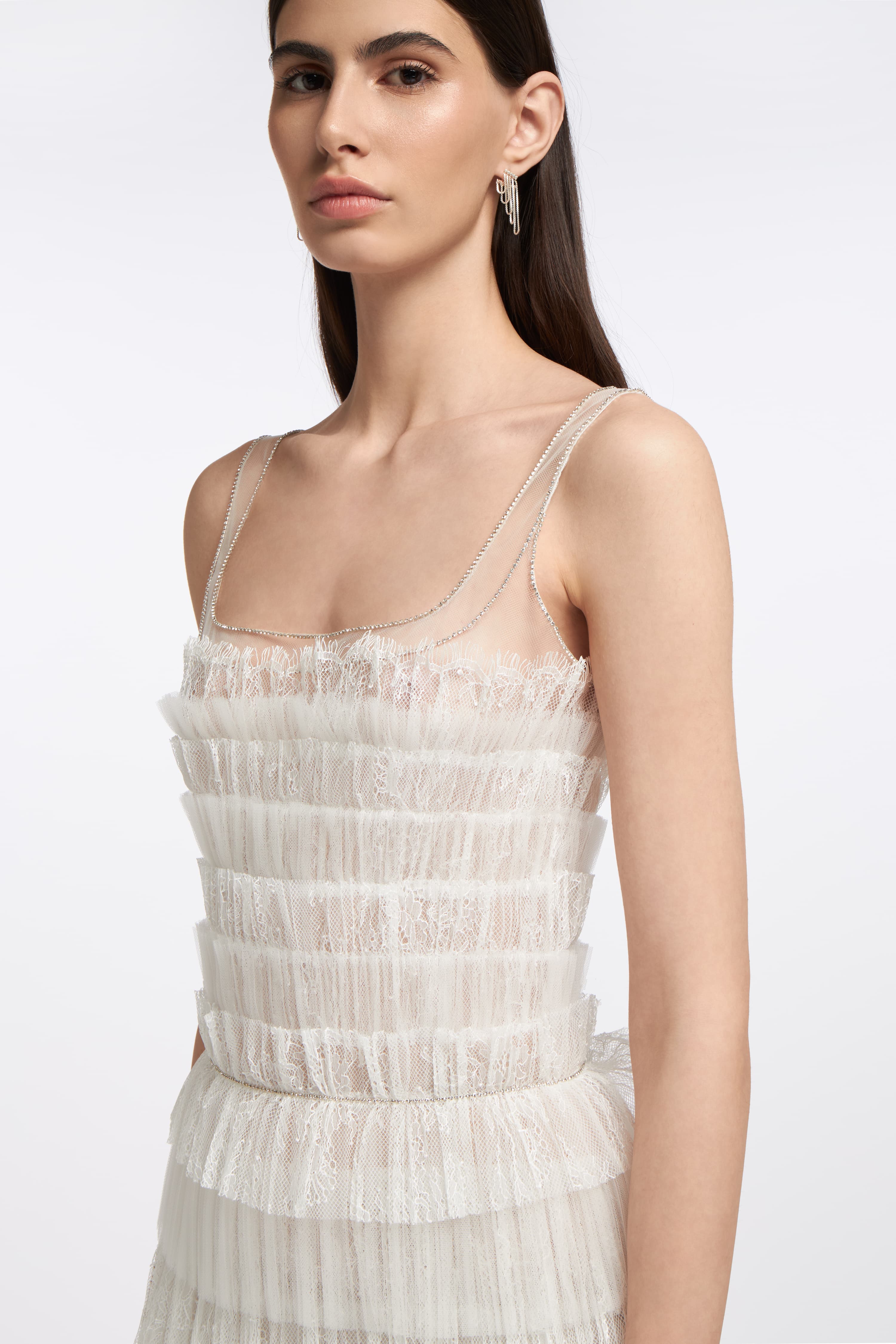 Close-up of the Galatea Plissé Lace Gown showcasing intricate pleated lace detailing, sheer tulle accents, and delicate spaghetti straps for an ethereal bridal style.