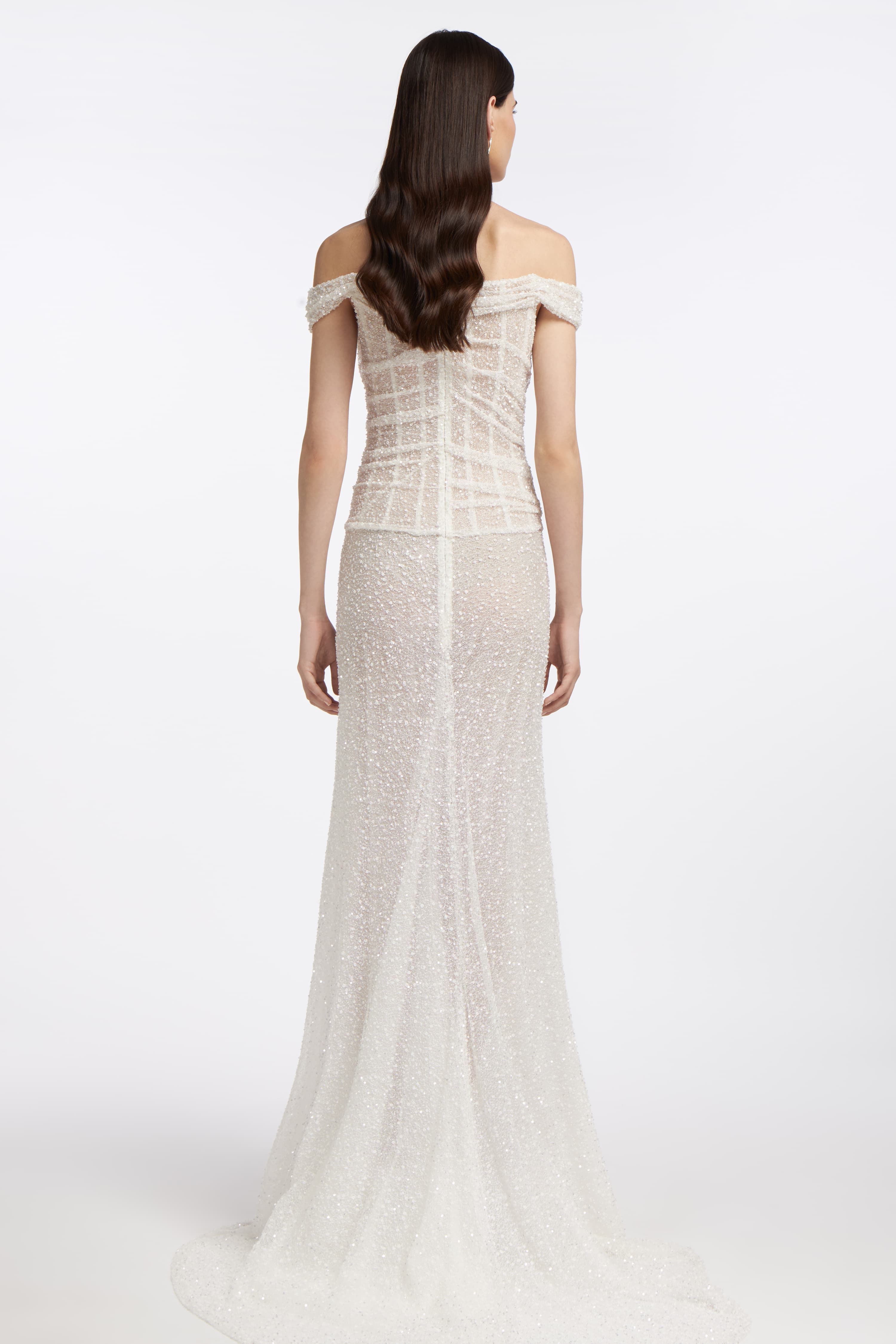 Back view of Clio Beaded Draped Gown with sheer beaded fabric, corset-style bodice, and flowing train. A sophisticated wedding dress for Spring 2025 brides.