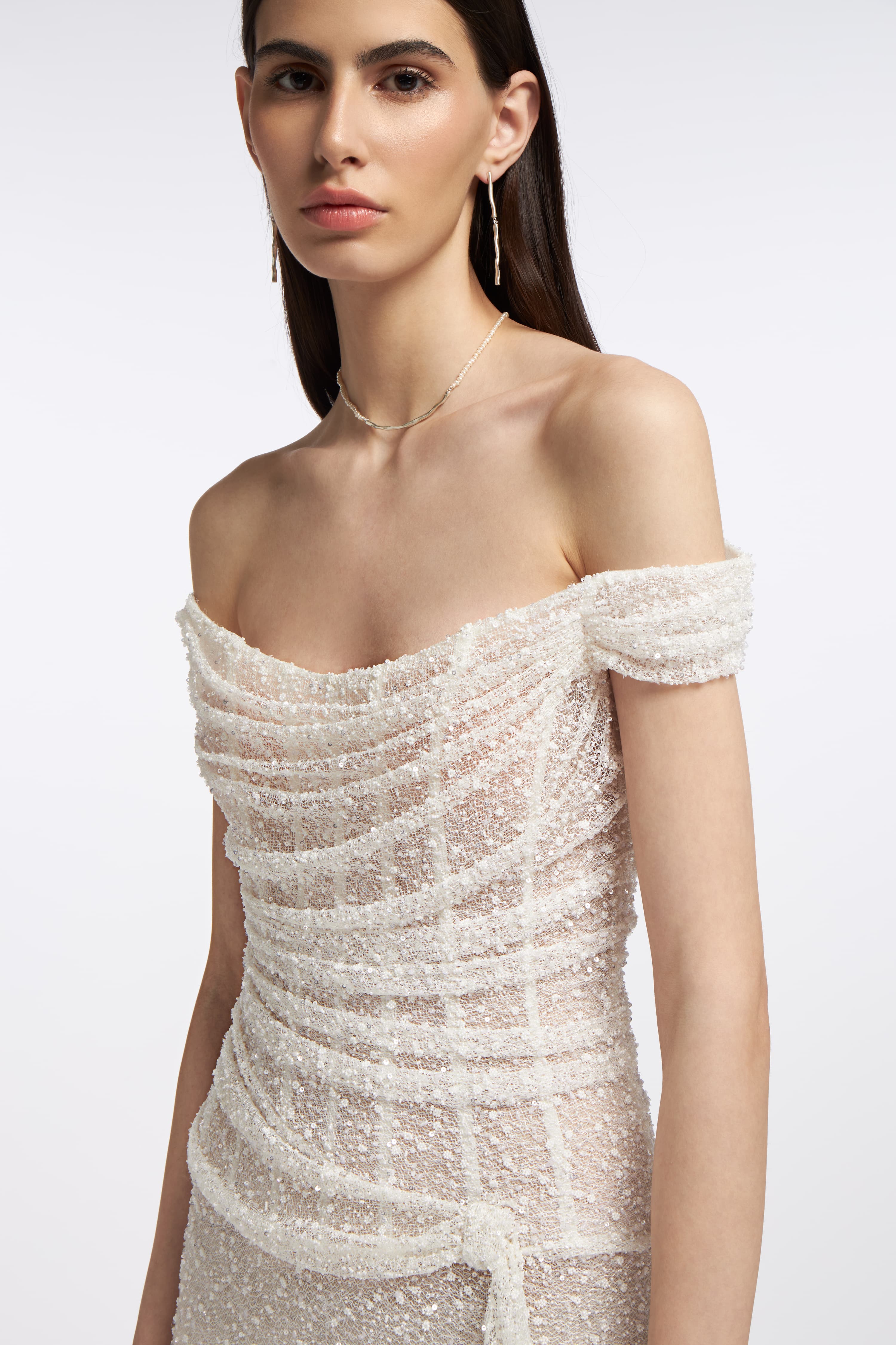 Close-up of Clio Beaded Draped Gown showcasing delicate beading, sheer detailing, and off-the-shoulder draped design. A stunning choice for bridal wear.