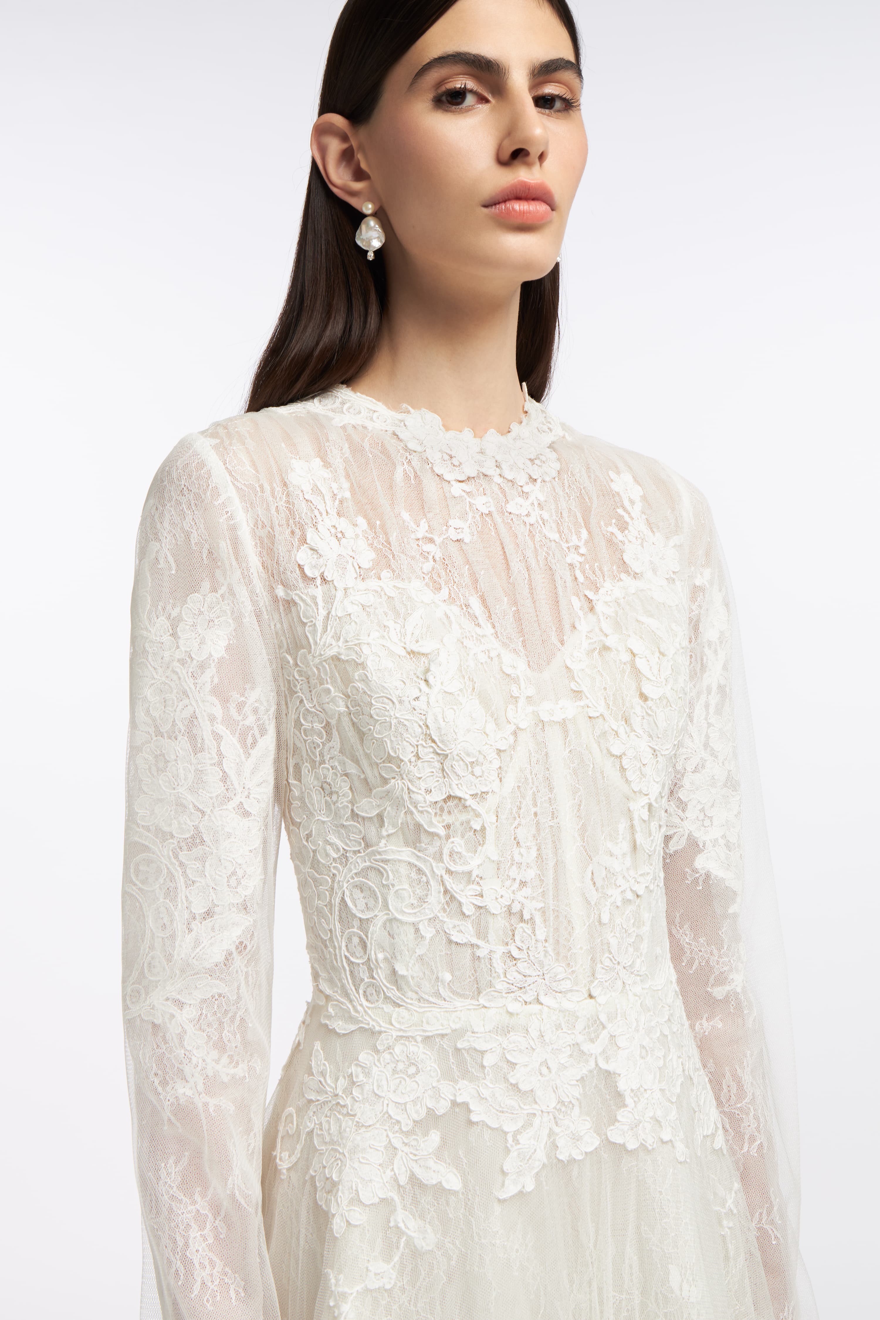 Close-up of the Elpis French Lace Gown showcasing intricate lace detailing, sheer bodice, and elegant floral appliqués for a romantic bridal style.