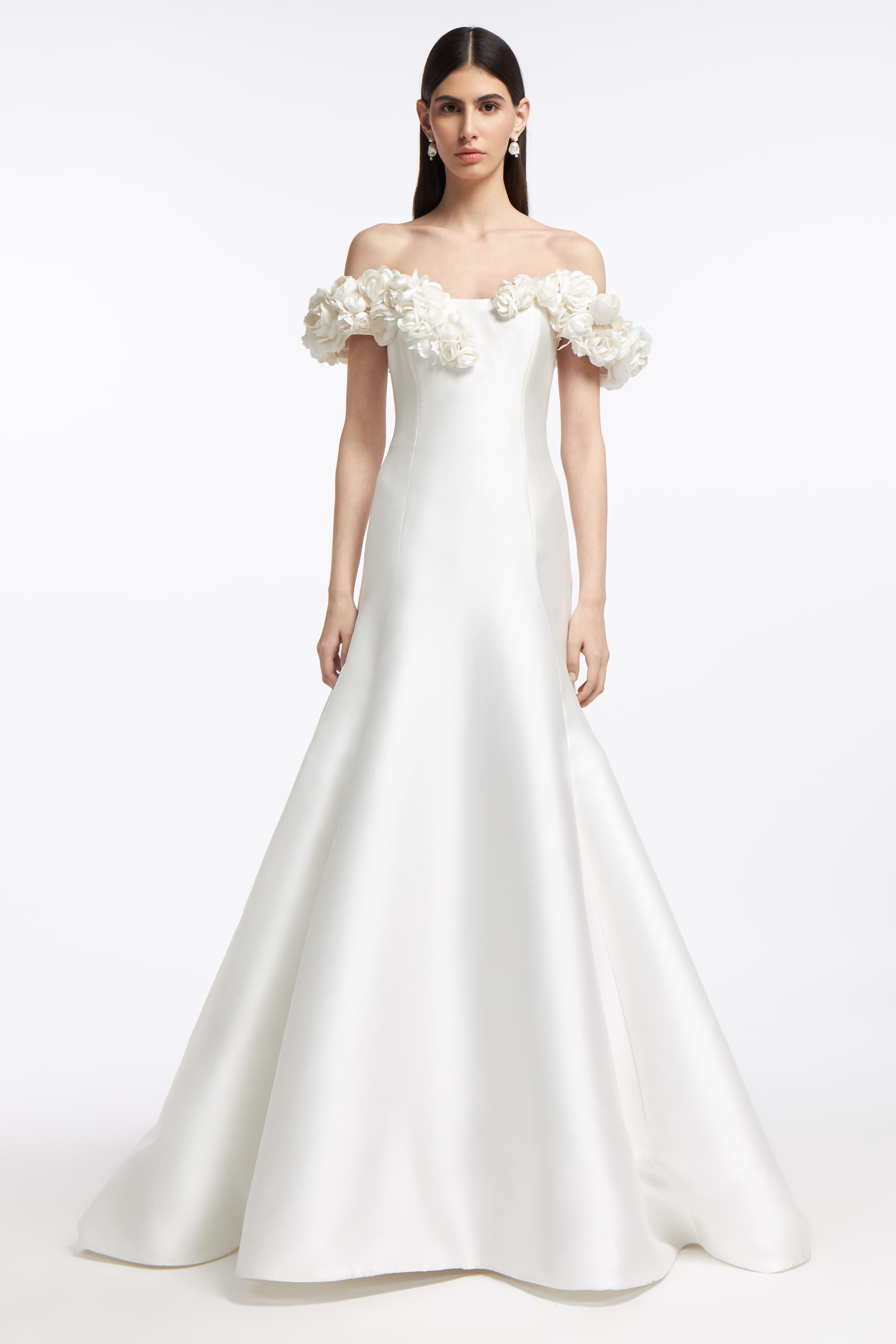 Harmonia Mikado Off-Shoulder Gown featuring a fitted bodice, floral appliqué sleeves, and a flowing A-line skirt. Perfect for a bridal look in Spring 2025.