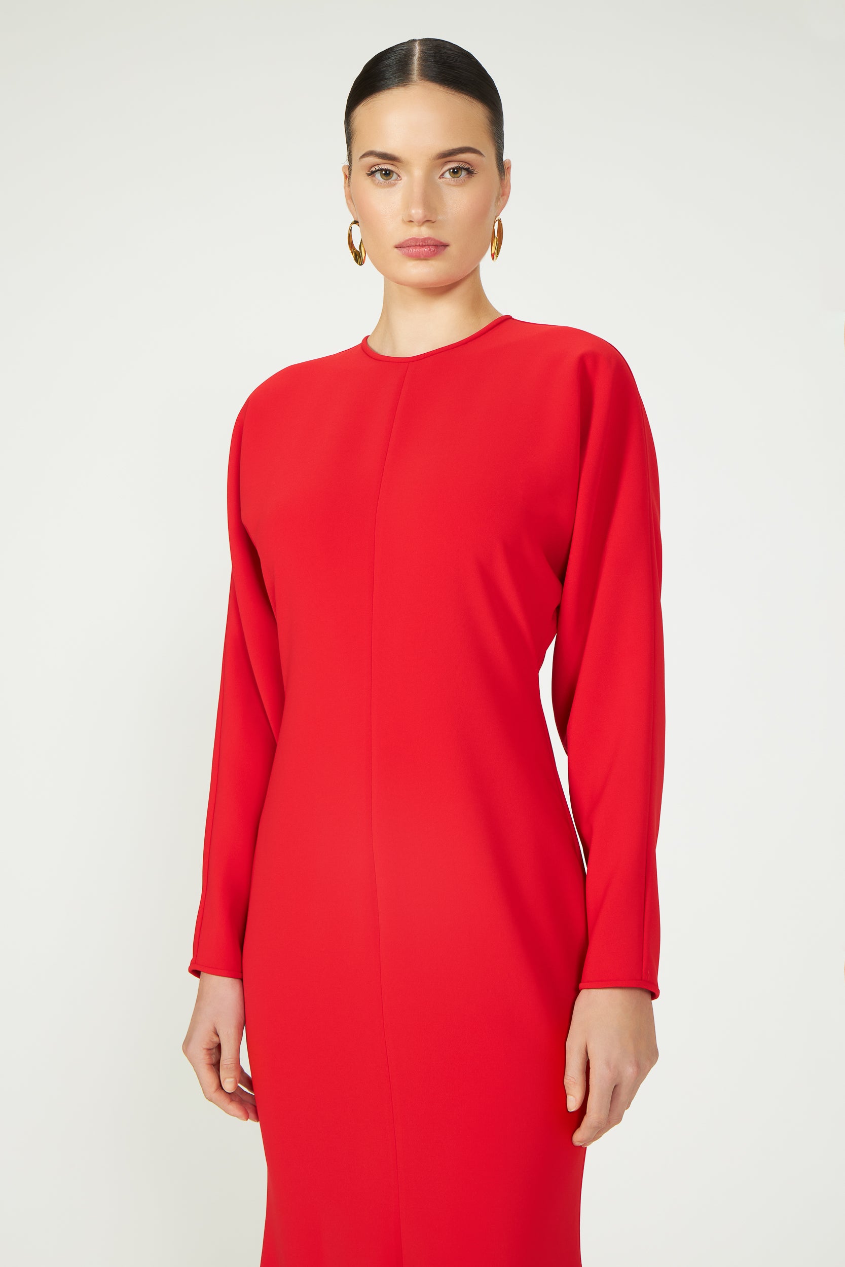 Close-up of the Marlette High-Low Crepe Gown showcasing its structured shoulders and refined long-sleeve design in vibrant red.