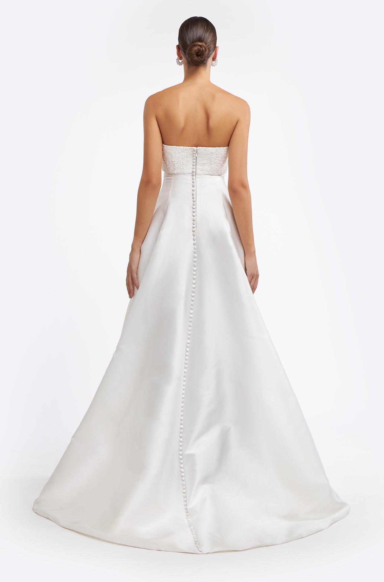 Back view of the Cornilia Strapless Mikado Gown with a row of delicate buttons and a flowing train. A timeless wedding dress for an elegant bridal look.