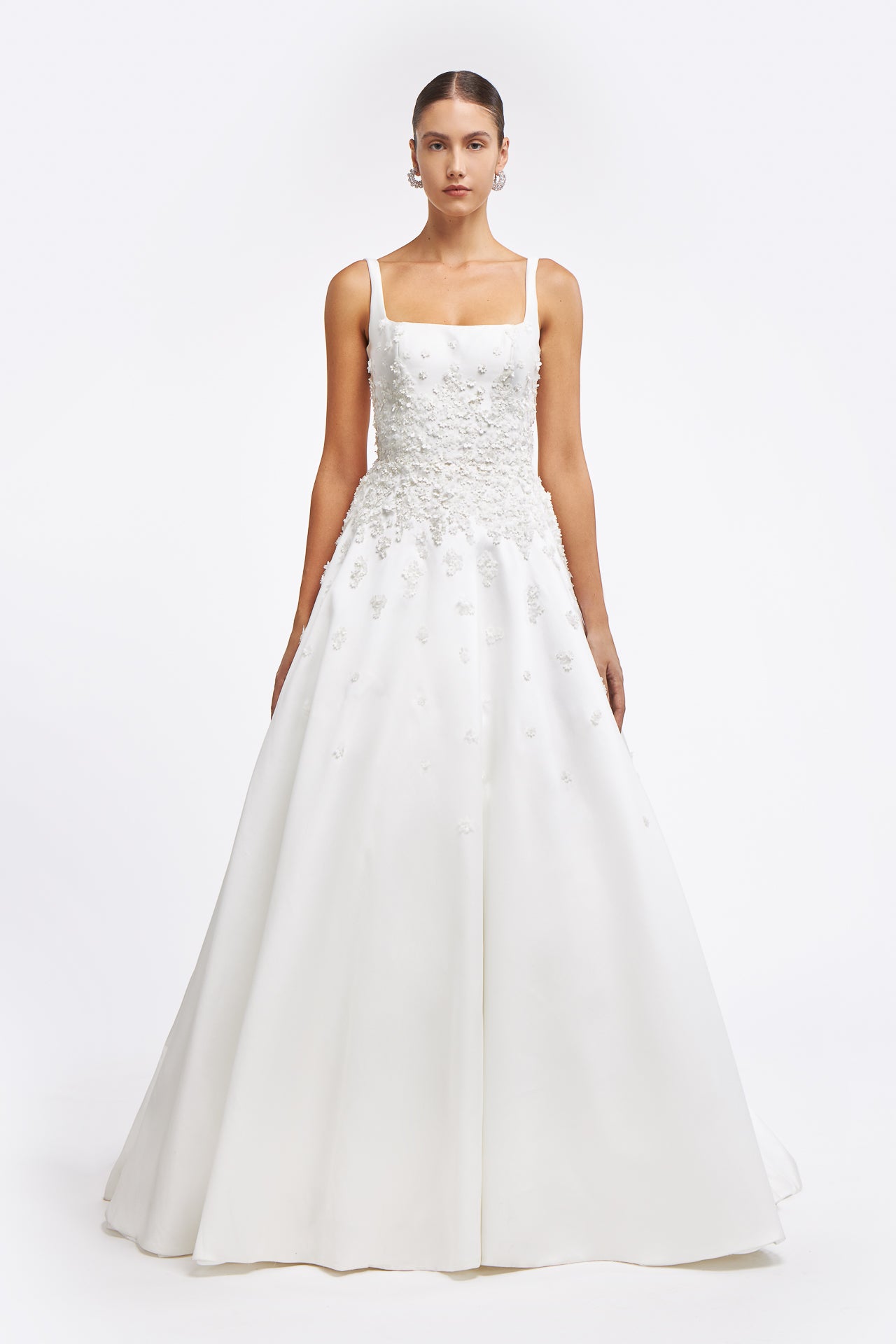 Clelia Mikado Gown featuring a square neckline, floral appliqué bodice, and an A-line silhouette. Elegant bridal gown from the Bridal Fall 2025 collection.