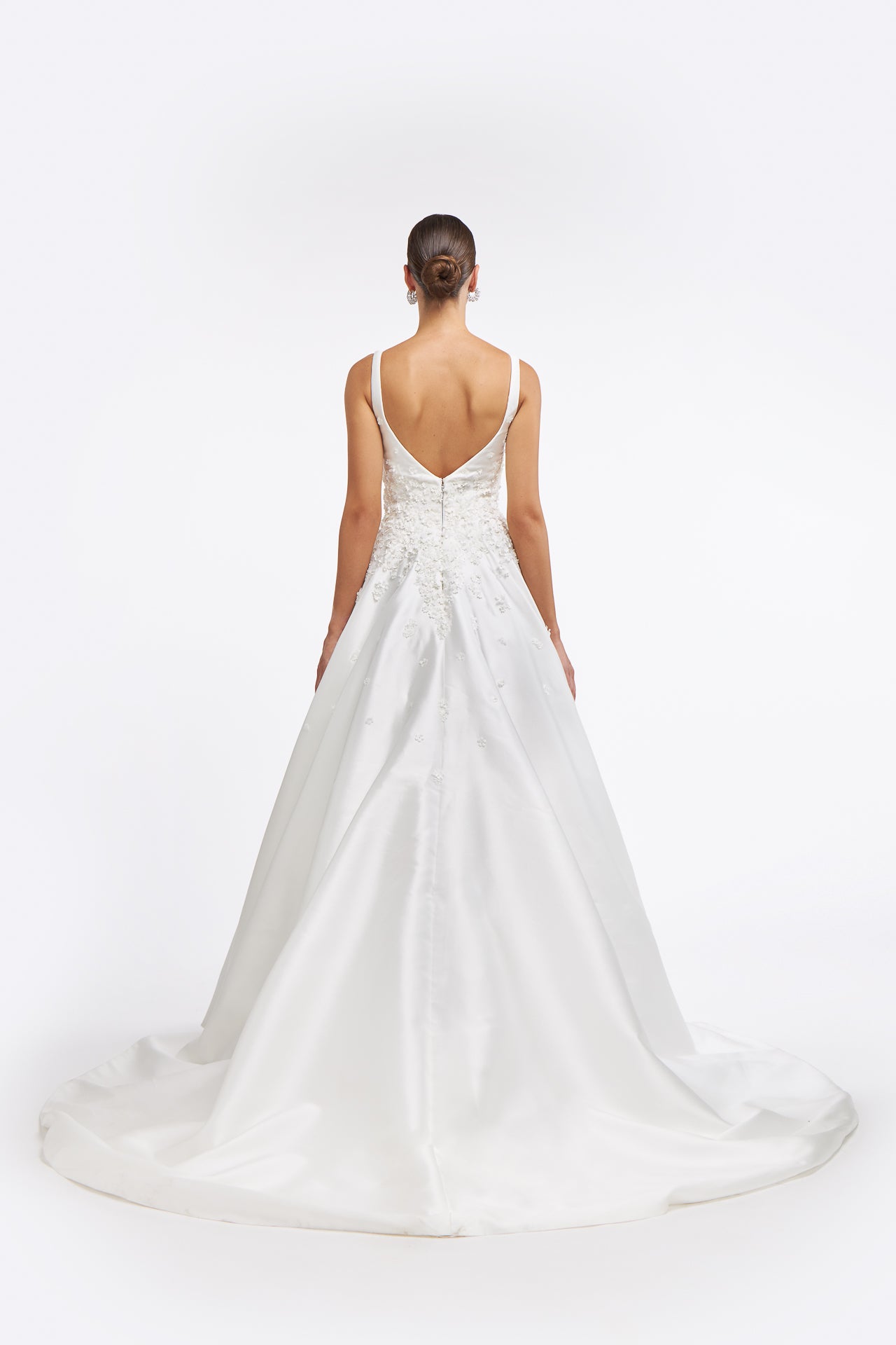 Back view of Clelia Mikado Gown with a deep V-back and flowing train. A timeless wedding dress with floral embellishments for a graceful bridal look.