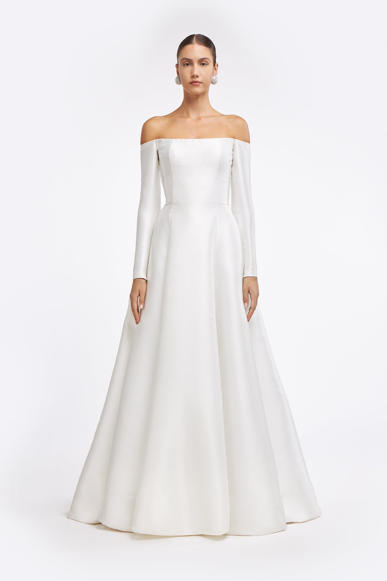 Berenice Off-shoulder Mikado Gown featuring a structured bodice and long sleeves. Elegant bridal gown with a flowing A-line skirt for a timeless look.