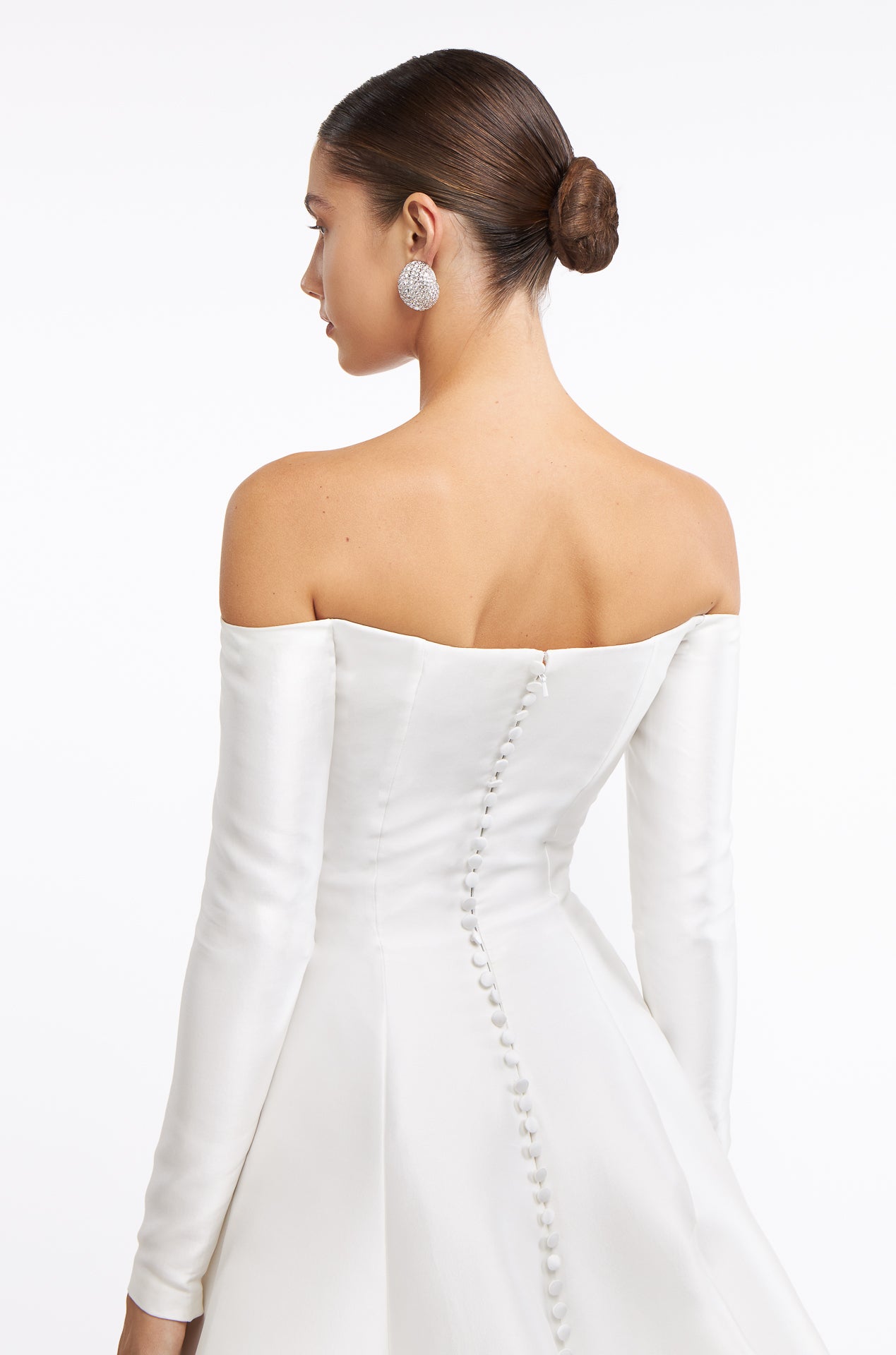Close-up of the Berenice Off-shoulder Mikado Gown showcasing delicate button details along the back. A sophisticated bridal gown with a sleek silhouette.