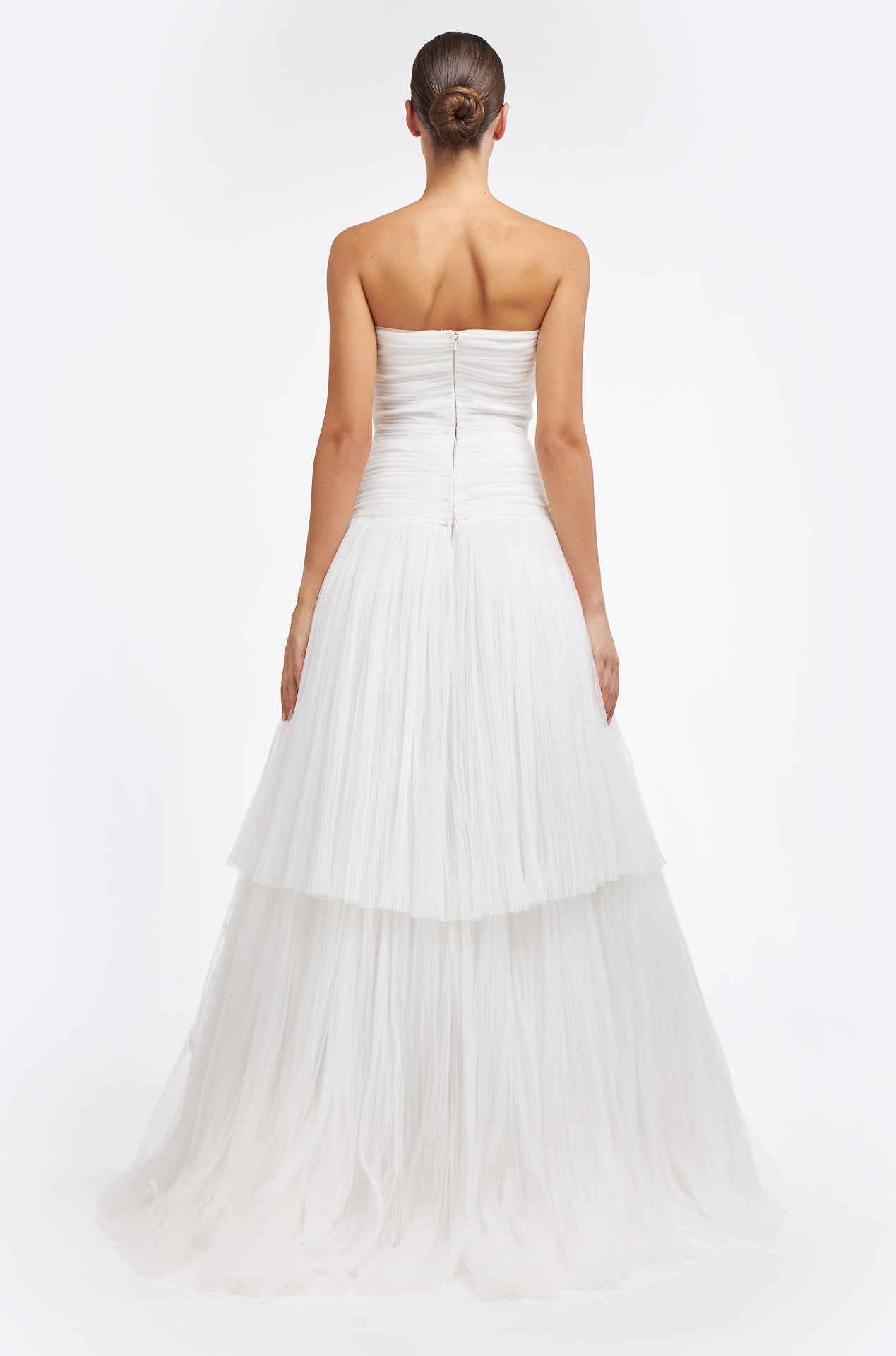 Back view of the Zinovia Plissé French Tulle Gown showcasing a fitted bodice with a concealed zipper and a flowing layered tulle skirt. Perfect for a bridal ensemble.