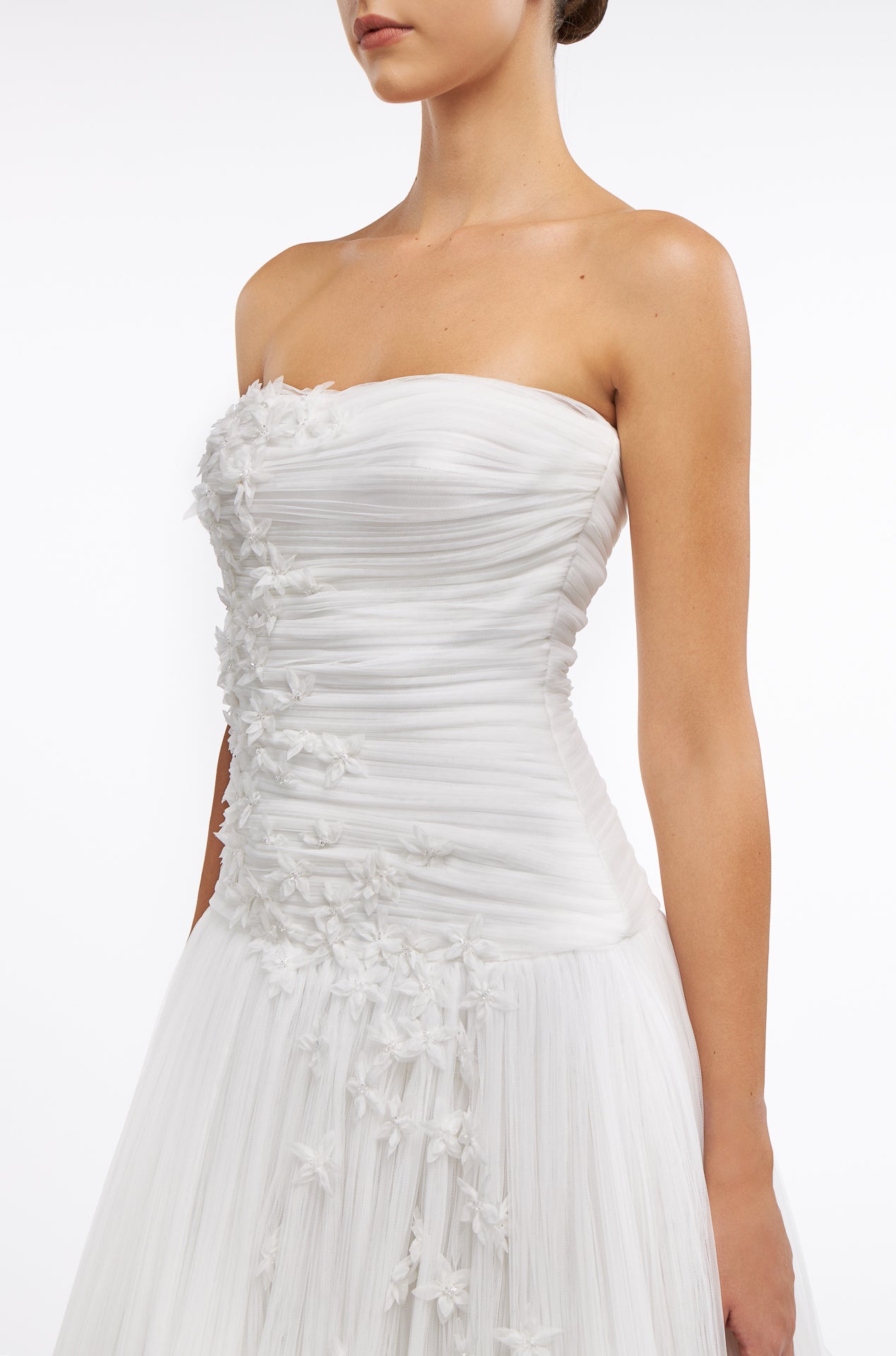 Close-up of the Zinovia Plissé French Tulle Gown's strapless ruched bodice adorned with intricate floral appliqués. Elegant bridal design for Fall 2025.