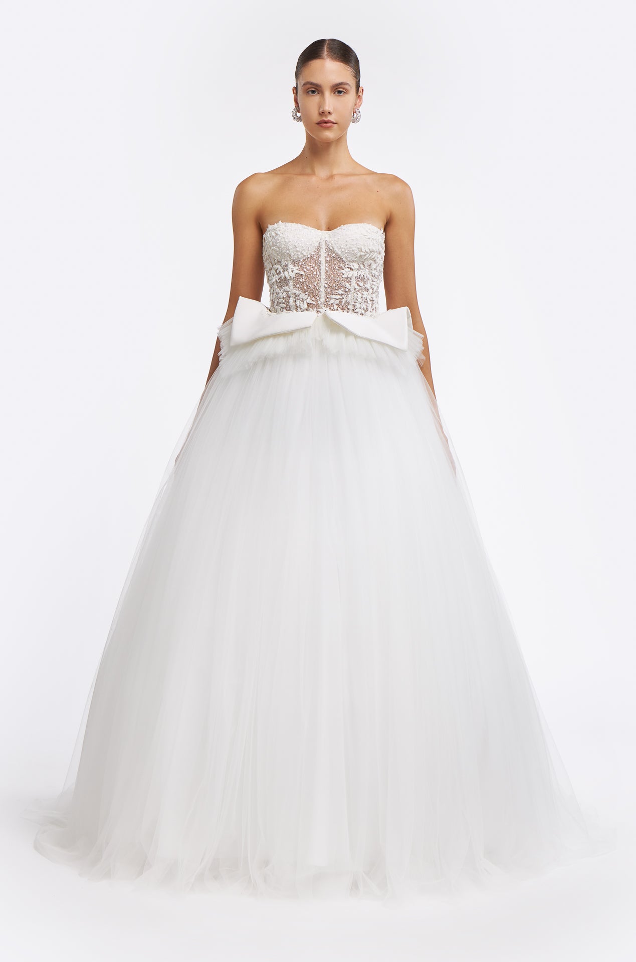 Emmelia French Tulle Gown featuring a strapless corset bodice with floral lace appliqués and a voluminous tulle skirt. Elegant bridal design for Fall 2025.