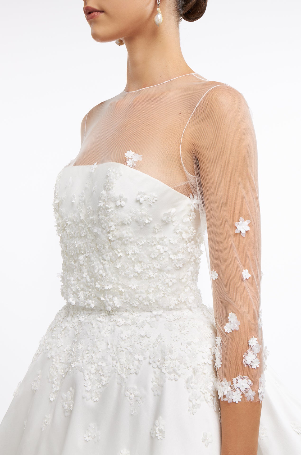 Close-up of Vasia Mikado Strapless Gown with sheer illusion sleeves adorned with delicate floral appliqués. A romantic bridal look for Spring 2025.
