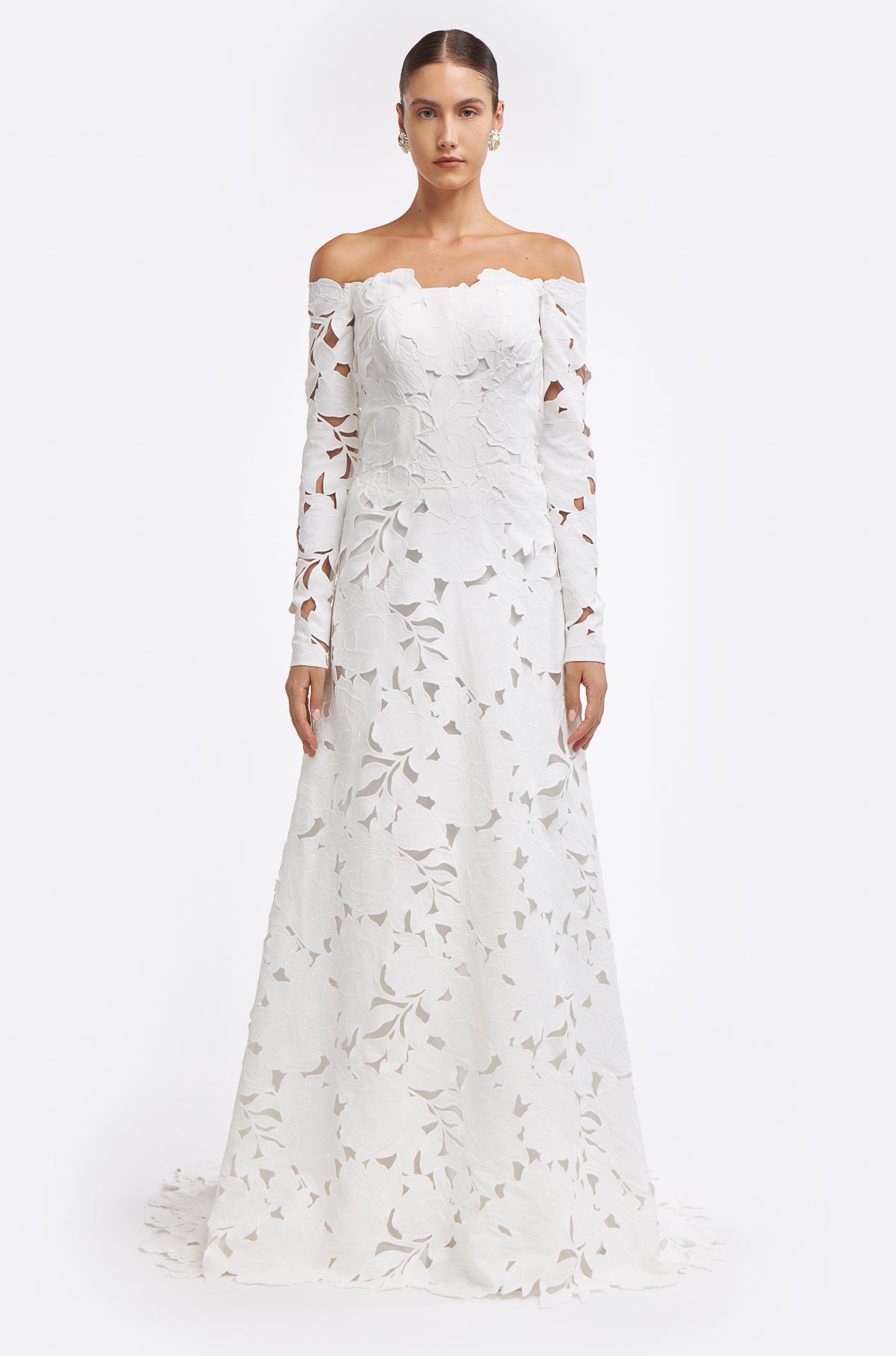 Oriane Floral-Cut Lace Gown featuring an off-the-shoulder neckline, long sleeves, and intricate floral lace detailing. A fitted bodice flows into an elegant A-line skirt.